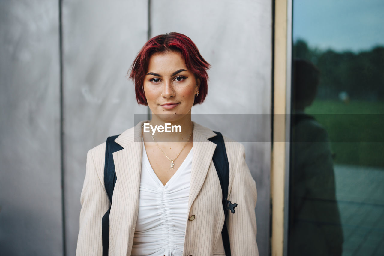 Portrait of female university student against gray wall