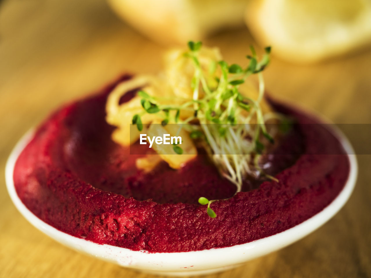 Close-up of beetroot hummus with sprouts in bowl on cutting board