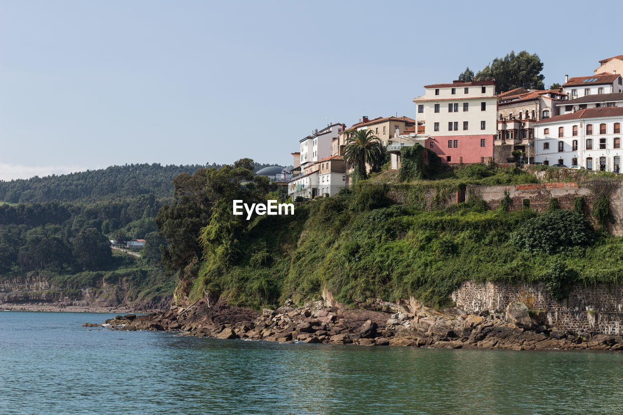 Buildings by sea against clear sky