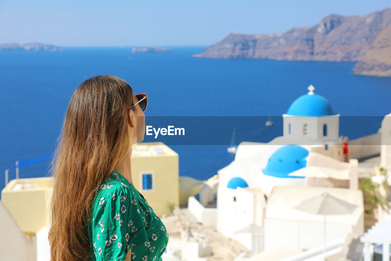 Side view of woman looking at houses and sea