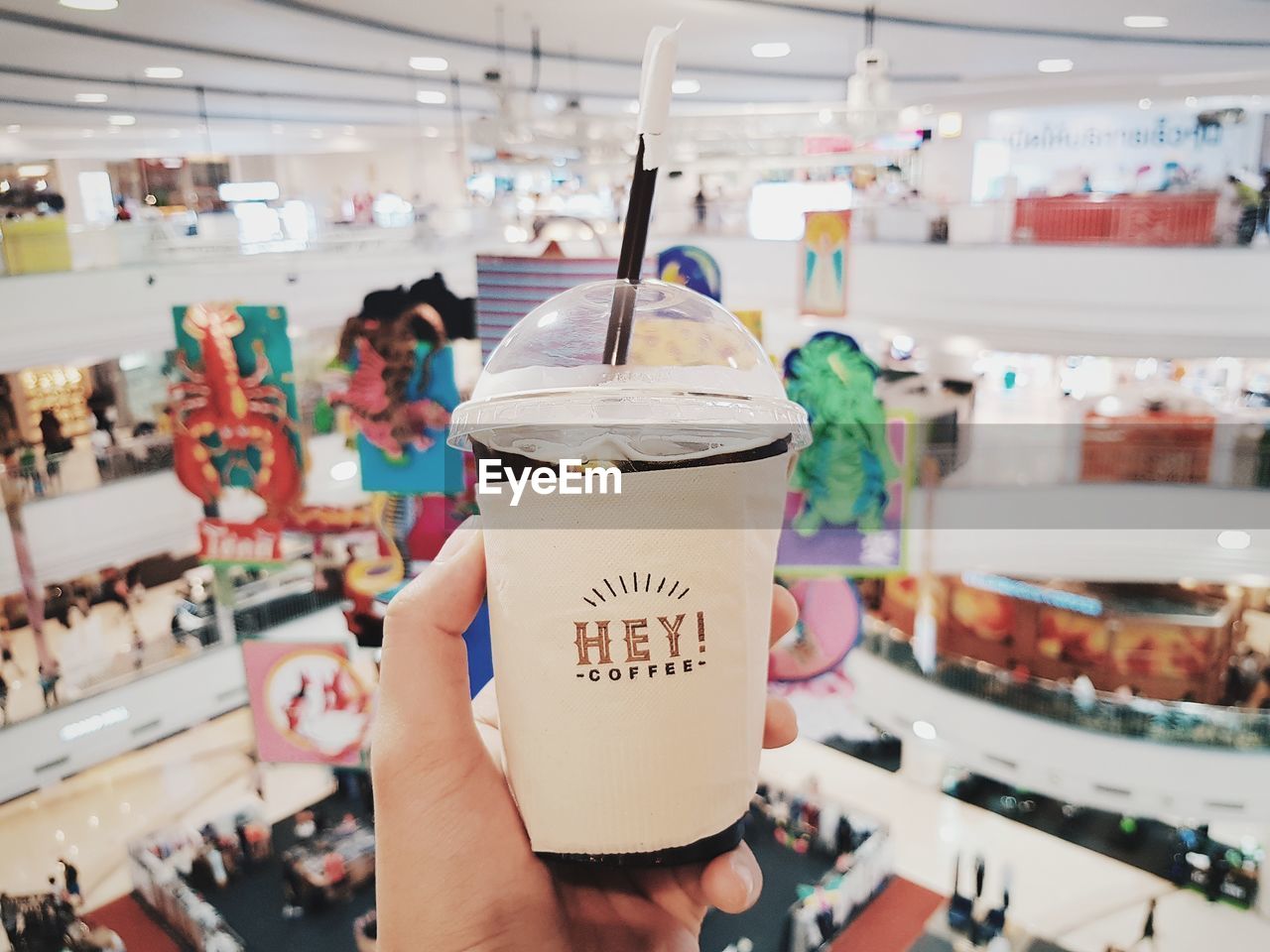 Cropped hand holding disposable cup in shopping mall