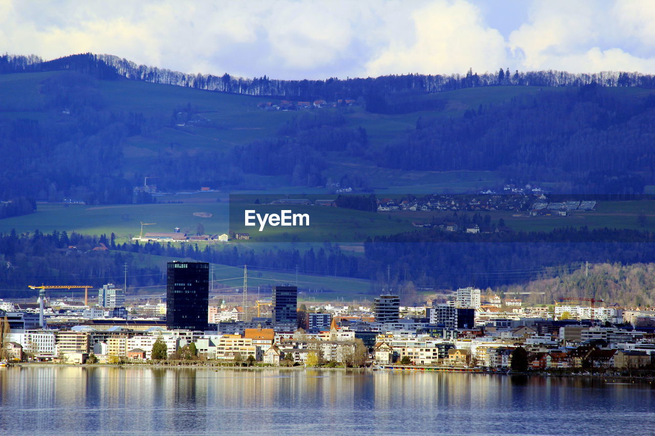 BUILDINGS BY LAKE AGAINST SKY