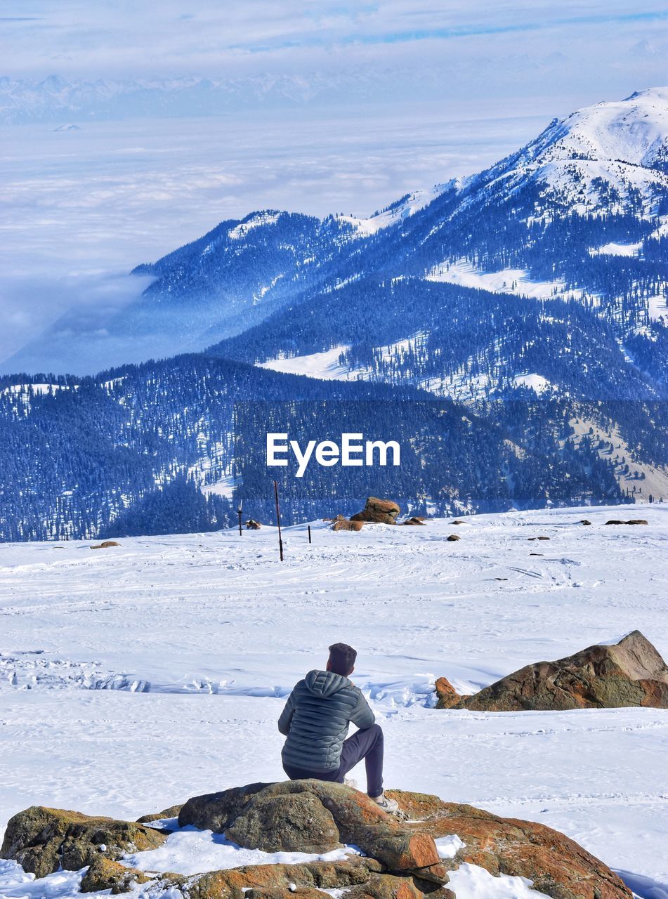 Rear view of person looking at snowcapped mountain