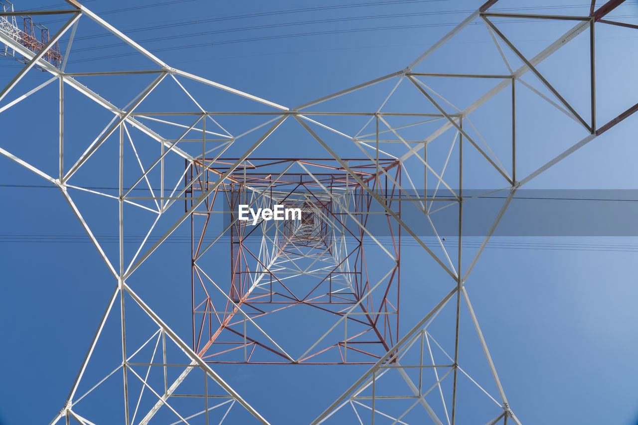 Low angle view of electricity pylon against blue sky