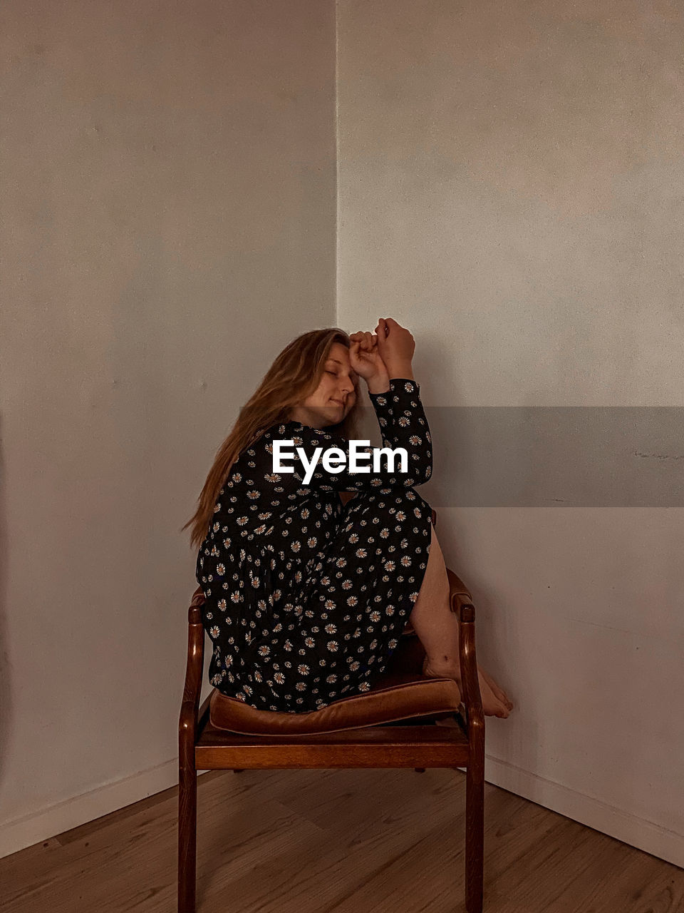 Woman sitting on chair against wall