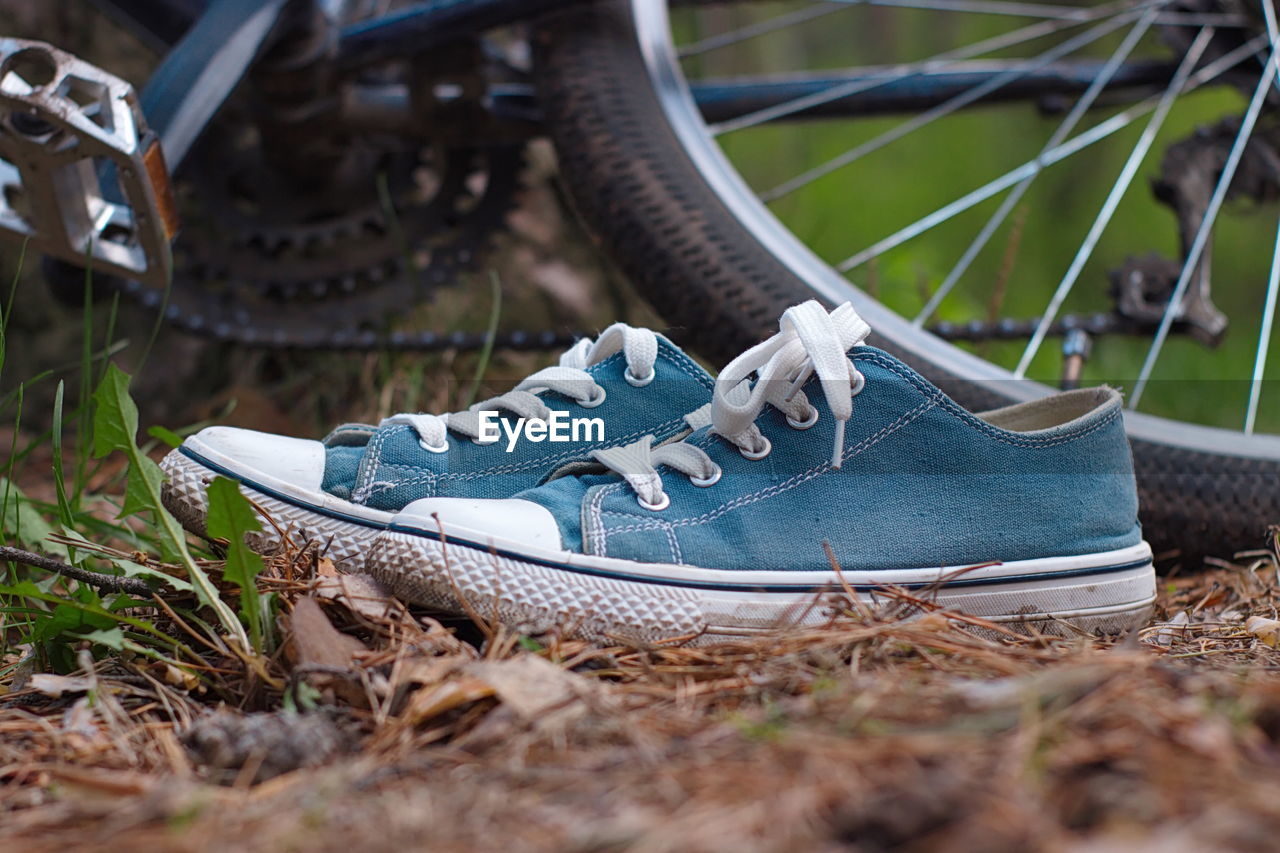 Close-up of canvas shoes against bicycles on field