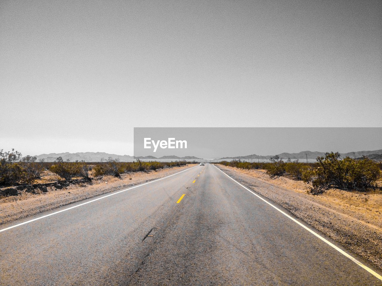 Diminishing perspective of empty road against clear sky during sunny day