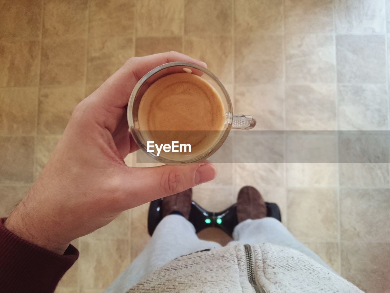 Cropped image of man holding coffee cup while riding segway pt at home