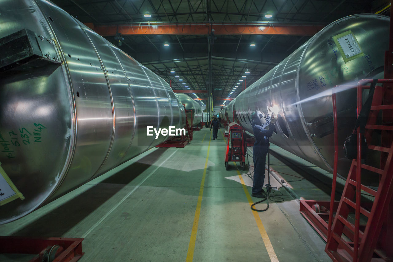 Man welding large steel tank in factory