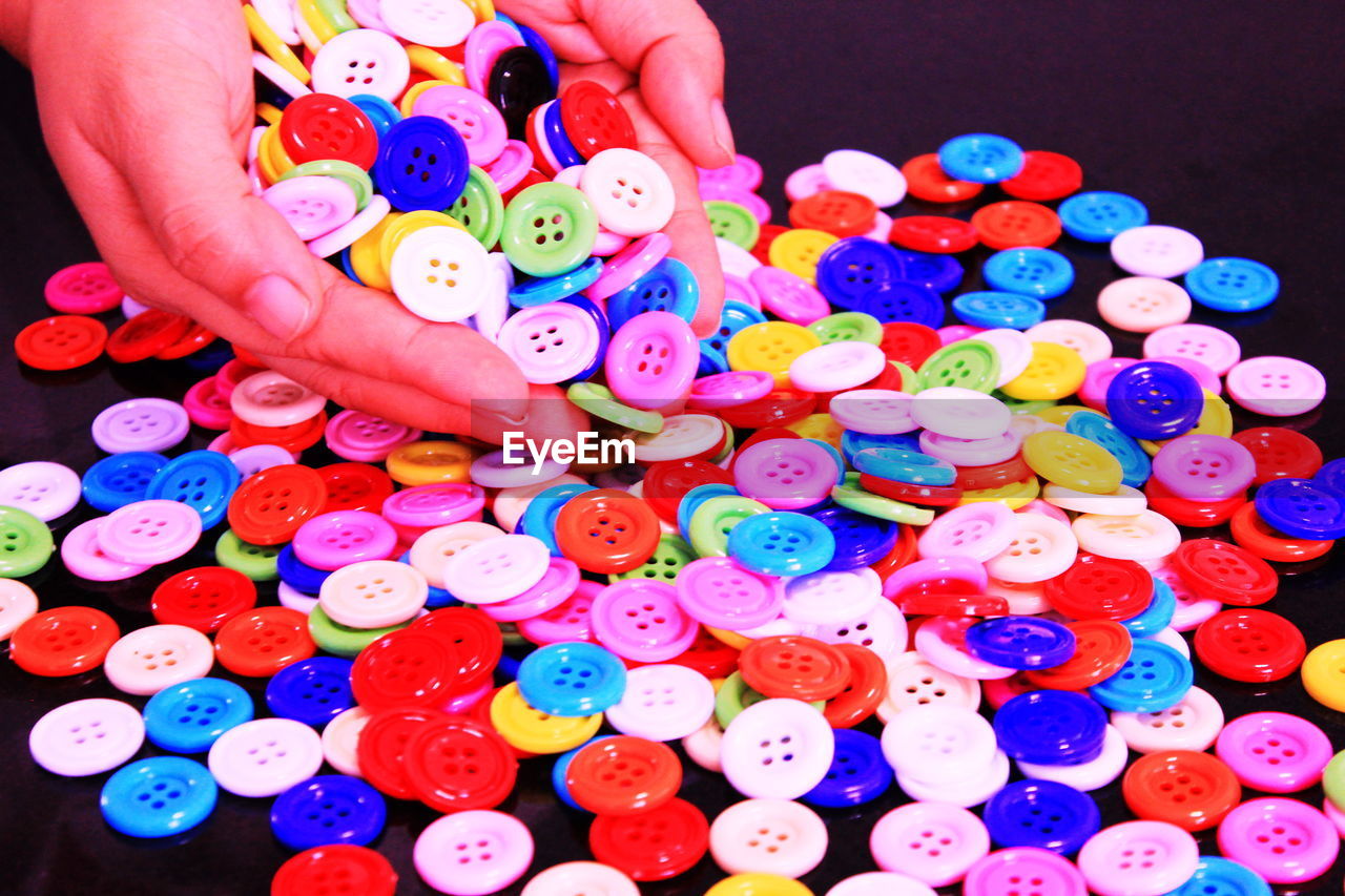 High angle view of hand holding multi colored buttons