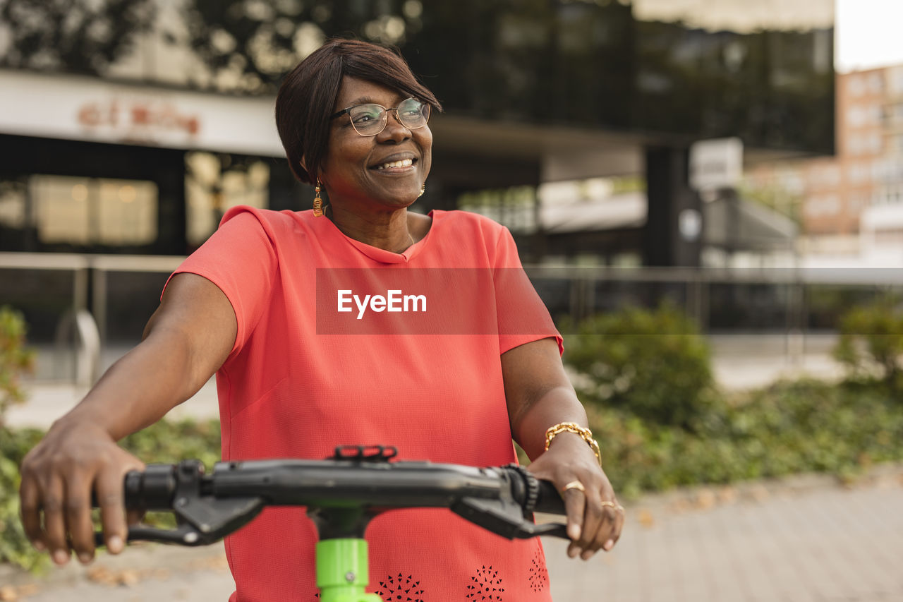 Smiling woman day dreaming with electric push scooter