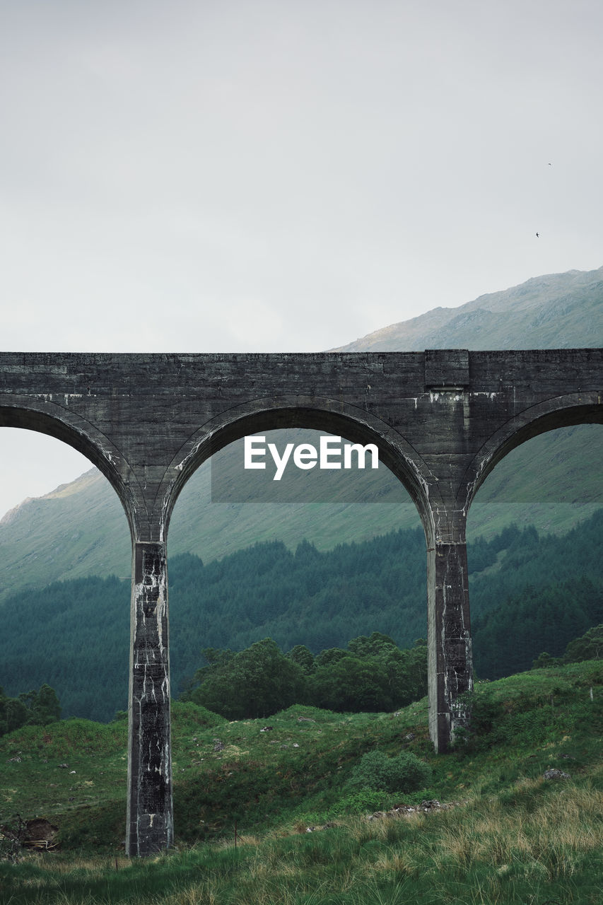 ARCH BRIDGE OVER MOUNTAINS AGAINST SKY