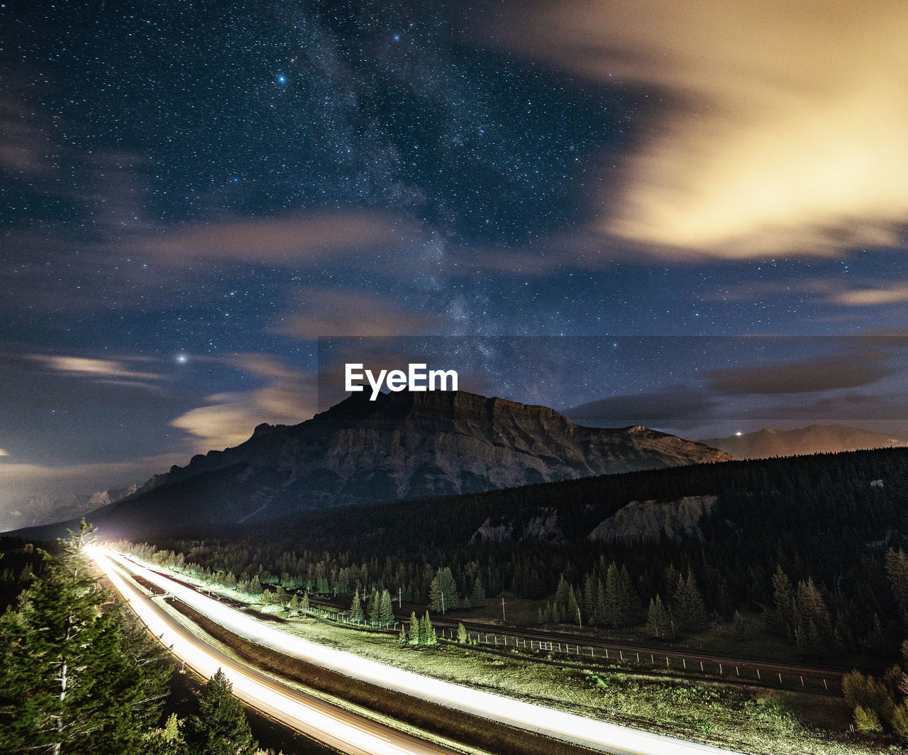 Milky way over rundle mountain with highway light stream