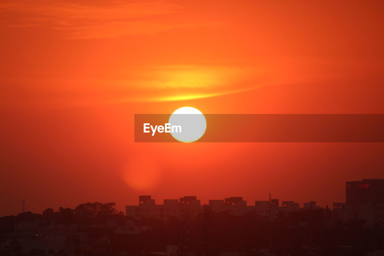 sky, sunset, horizon, afterglow, city, architecture, building exterior, sun, nature, cityscape, built structure, orange color, beauty in nature, dawn, sunlight, urban skyline, landscape, no people, building, scenics - nature, dramatic sky, astronomical object, outdoors, silhouette, cloud, red sky at morning, environment, tranquility, evening, red, travel destinations, residential district, idyllic, tranquil scene, city life, romantic sky, geometric shape