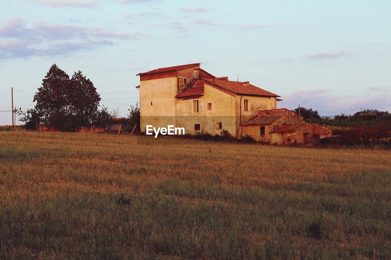 HOUSES ON FIELD AGAINST SKY