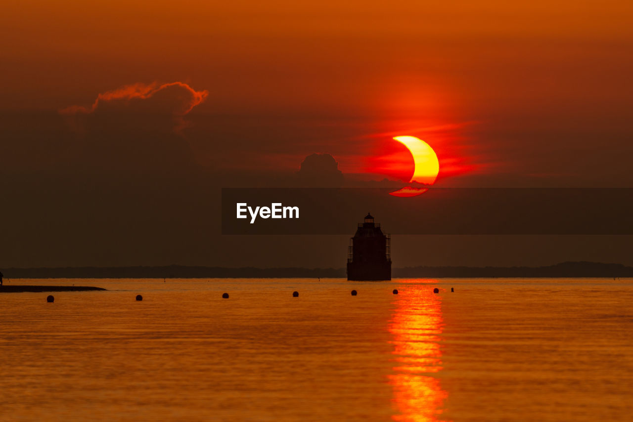 SILHOUETTE BUILDING BY SEA AGAINST ROMANTIC SKY DURING SUNSET