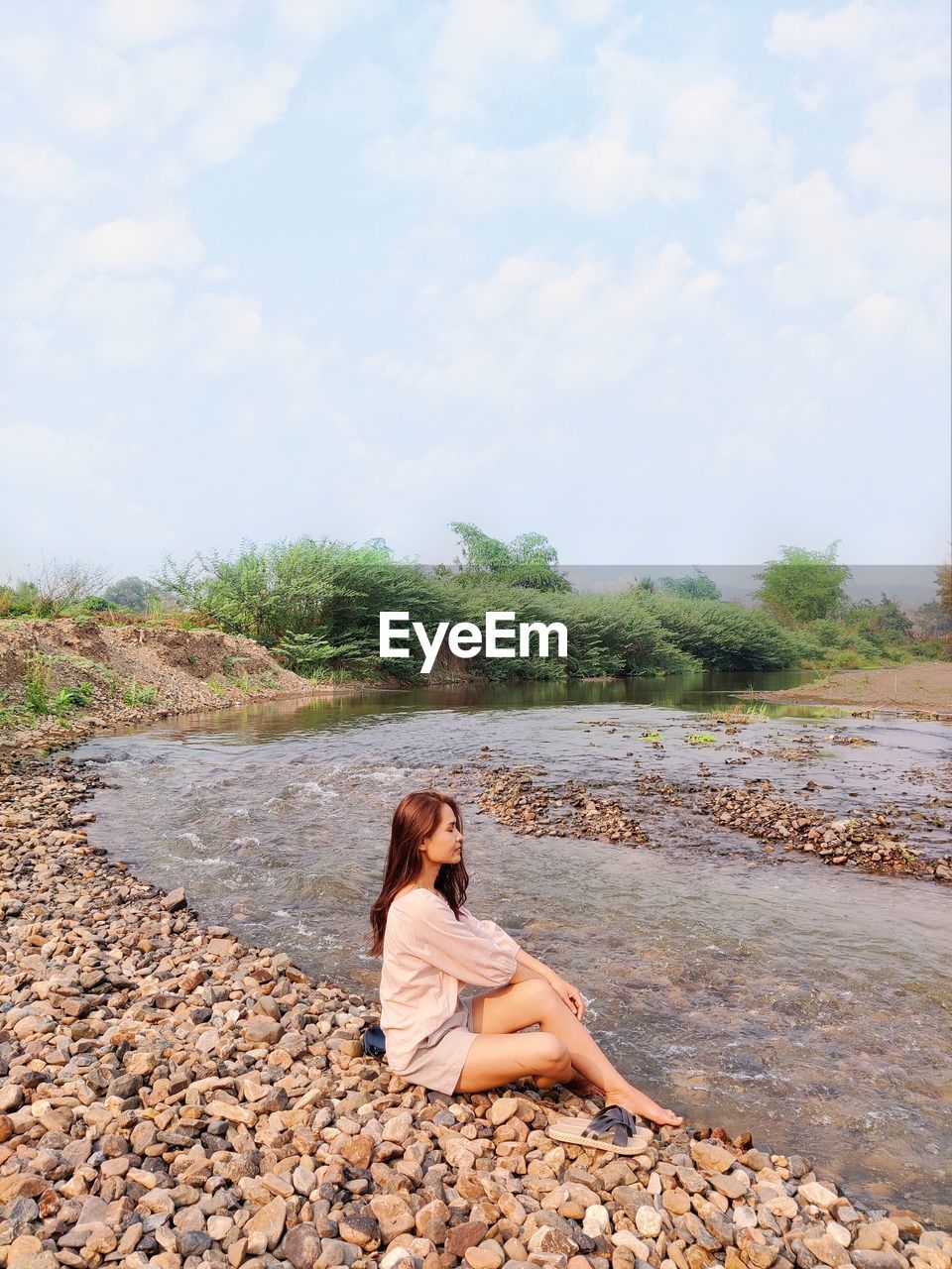 YOUNG WOMAN SITTING ON ROCK