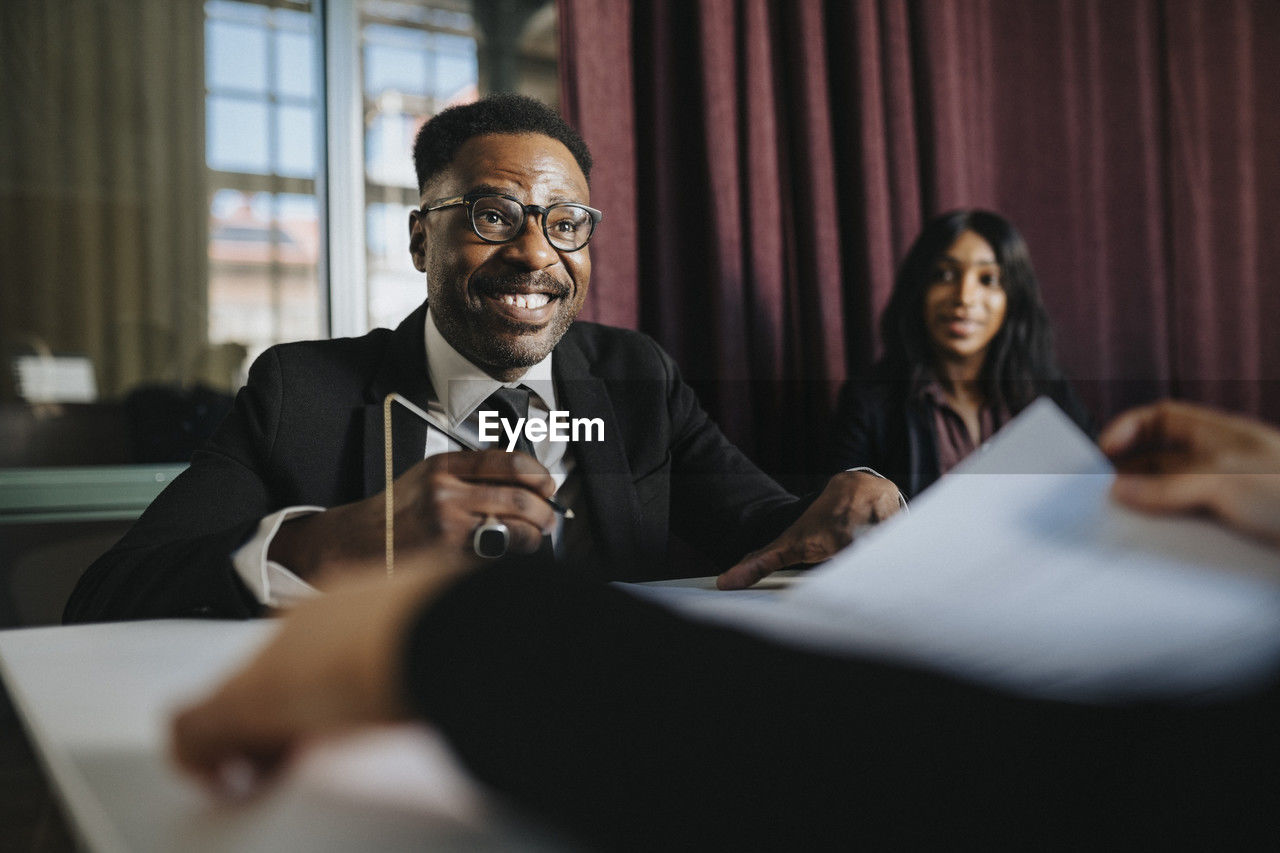 Happy mature businessman wearing eyeglasses in board room at office