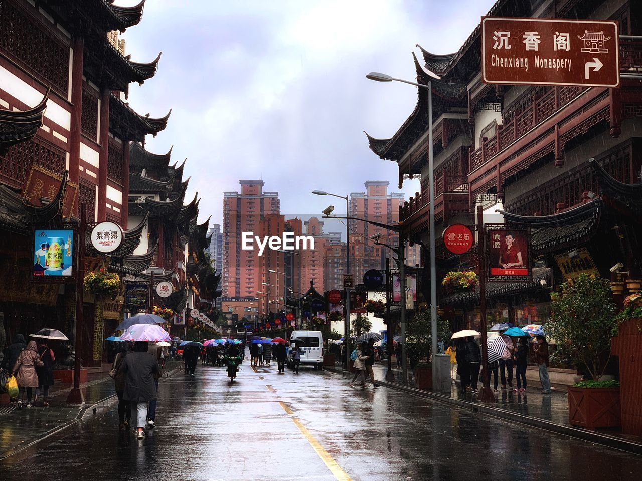 PEOPLE WALKING ON WET STREET IN CITY DURING MONSOON