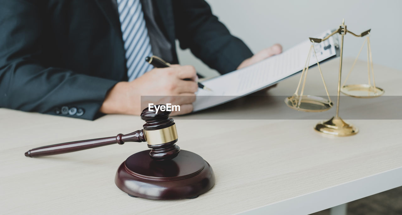 Midsection of lawyer holding gavel at table