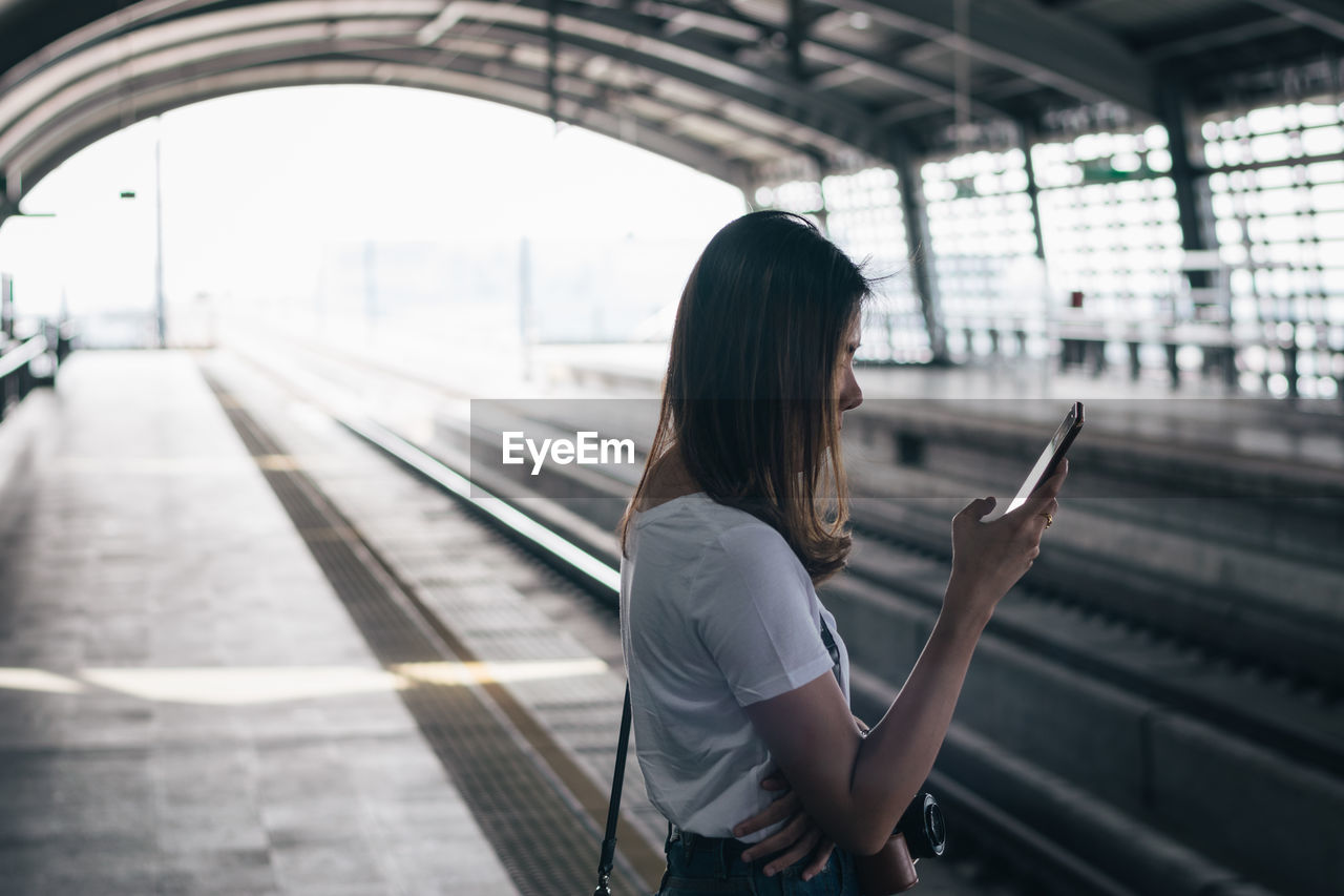 SIDE VIEW OF WOMAN ON RAILROAD STATION