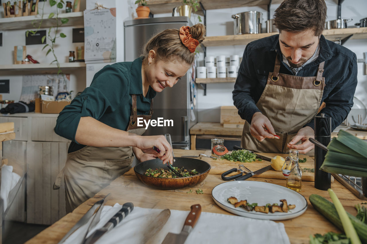 Chefs garnishing plate while standing in kitchen