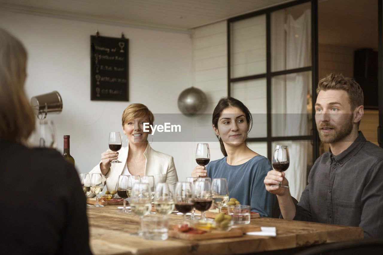 Smiling business people holding wineglass while sitting at table