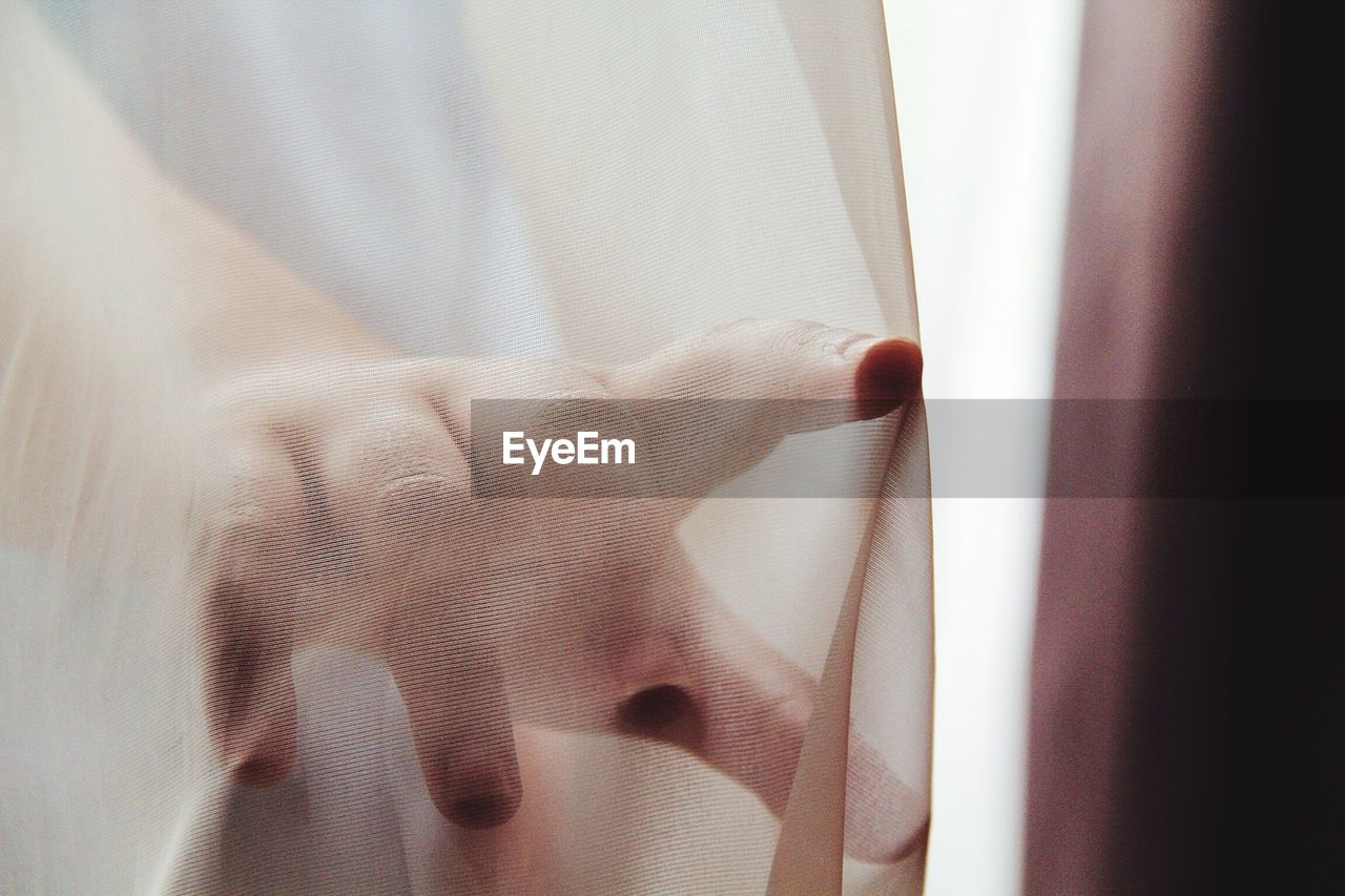 Close-up of hand touching curtain