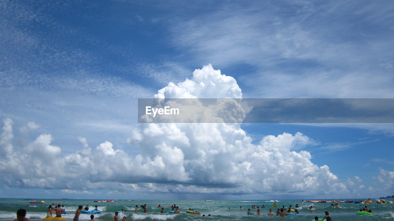 Panoramic view of people on beach against blue sky