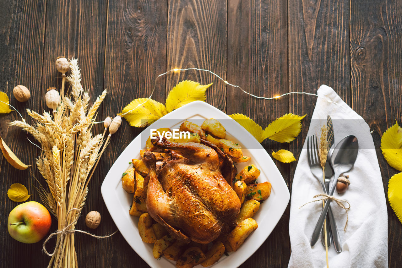 Autumn composition with leaves, ripe pumpkin and thanksgiving turkey on a dark wooden table.