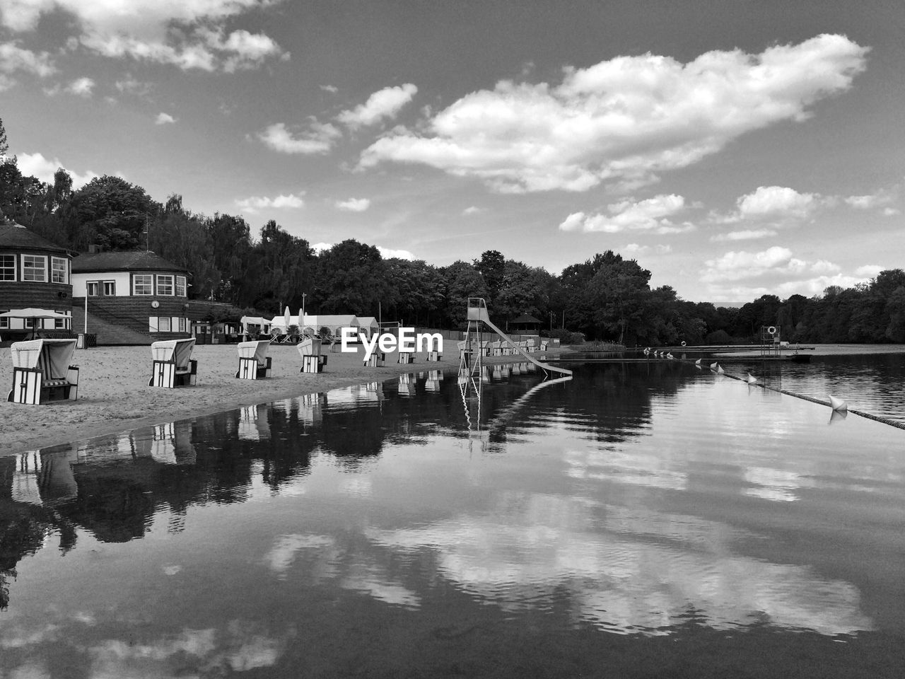 Hooded beach chairs on riverbank against sky