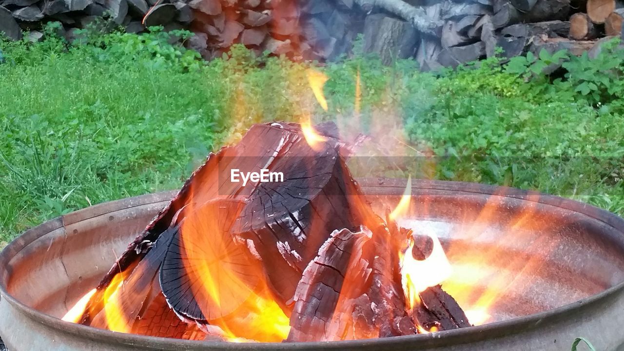 Close-up of wood burning in fire pit on field