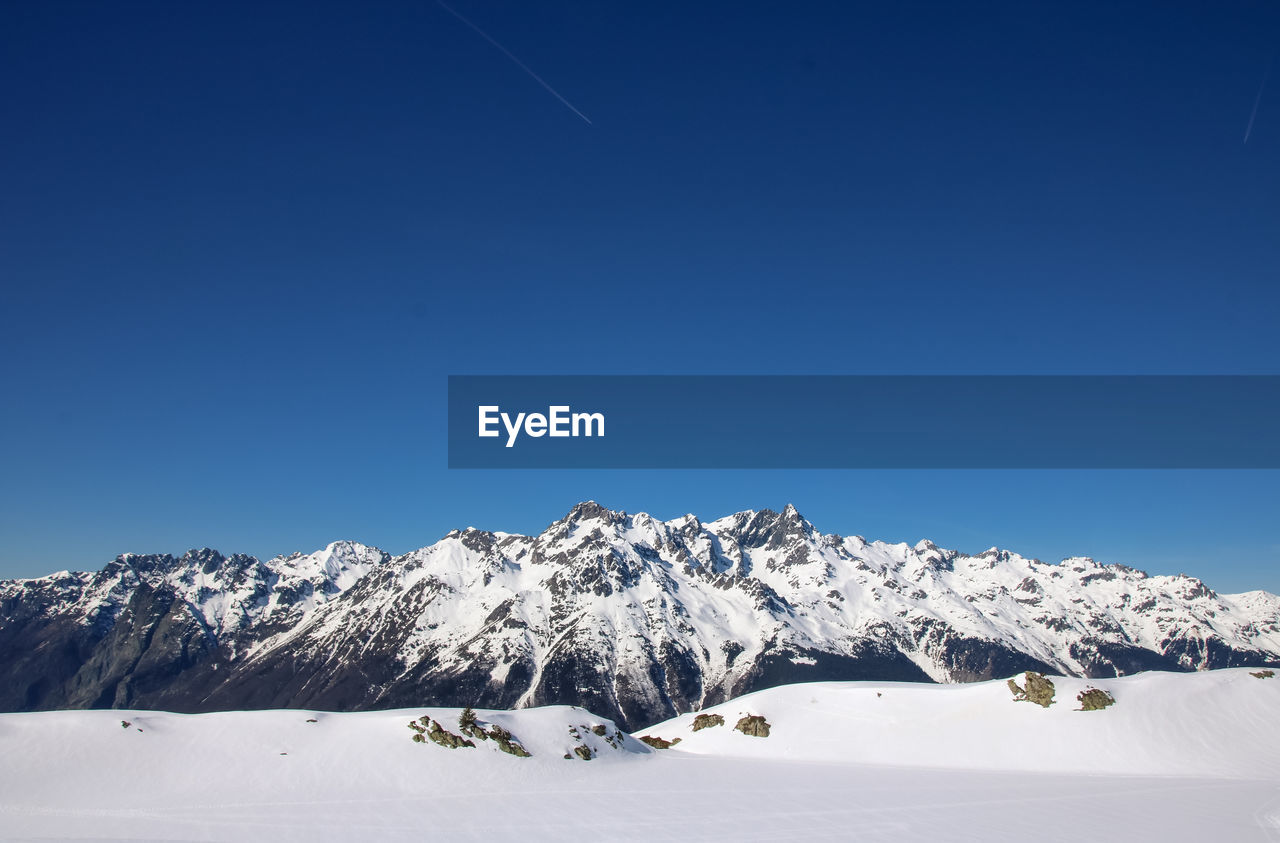 Snowcapped mountains against clear blue sky