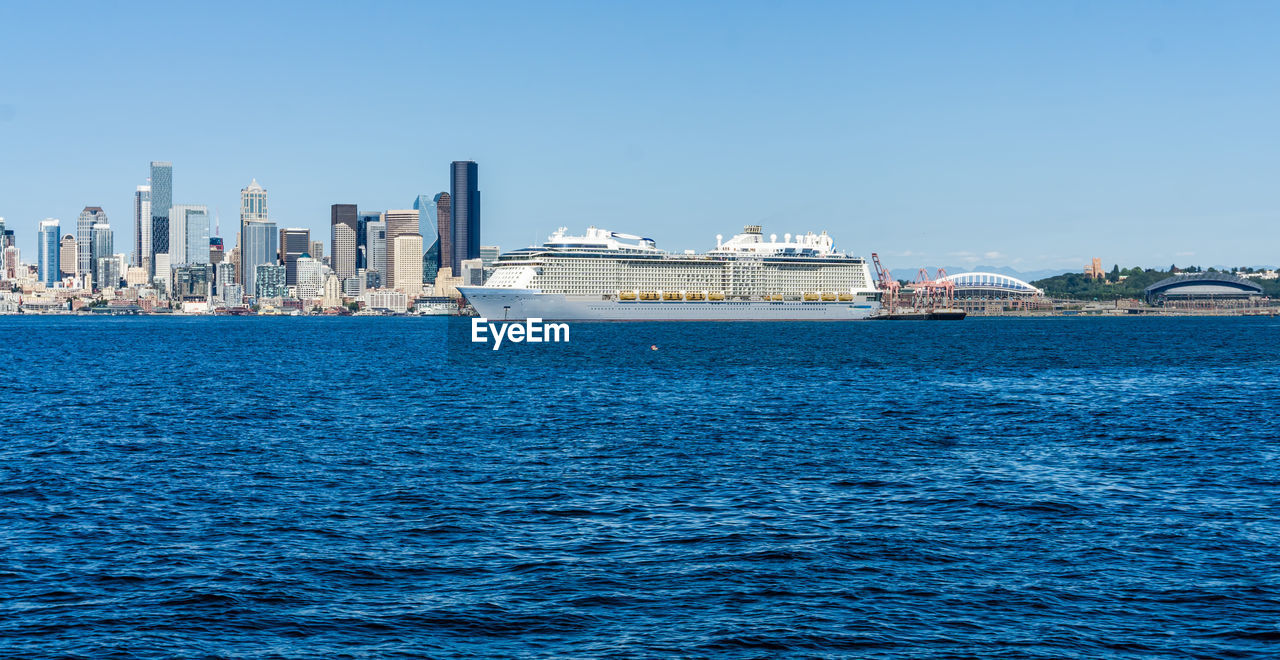A cruise ship is anchored in front of the seattle skyline.