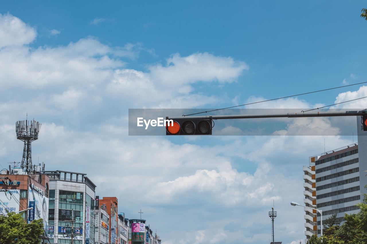 LOW ANGLE VIEW OF ROAD SIGNAL AGAINST CLOUDY SKY