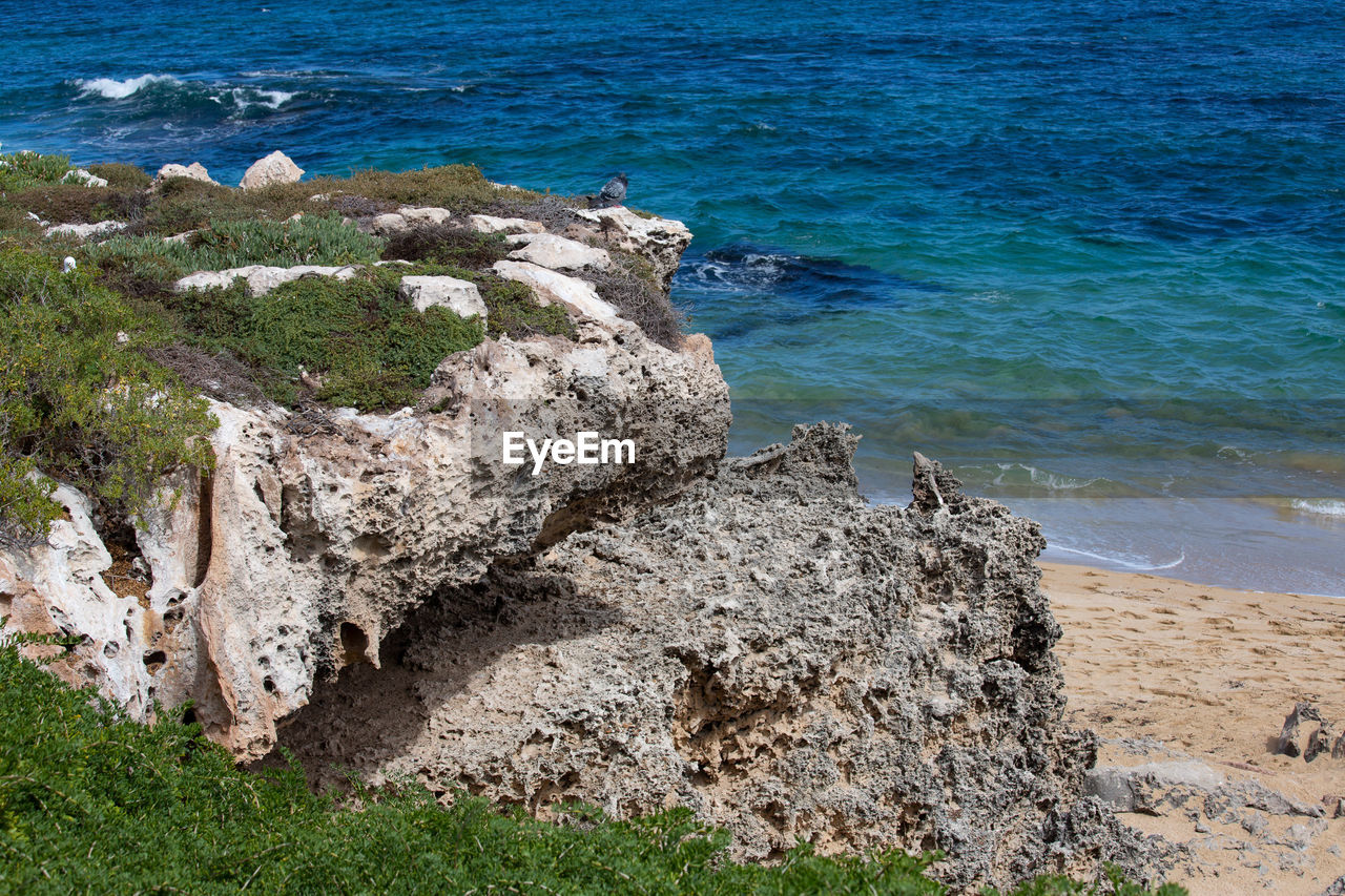 HIGH ANGLE VIEW OF ROCKS ON SHORE AT SEA