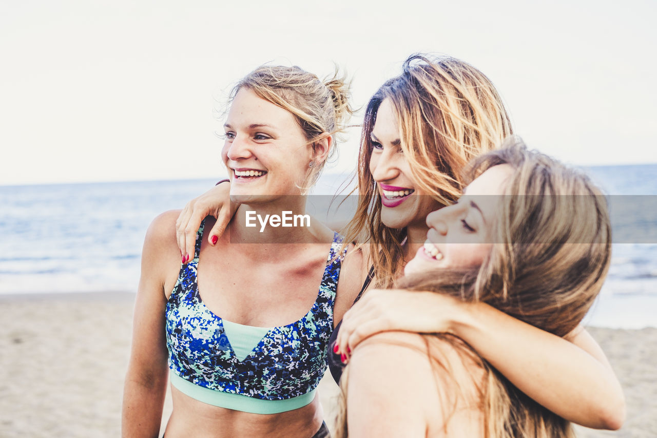 Happy friends wearing bikini while enjoying together at beach