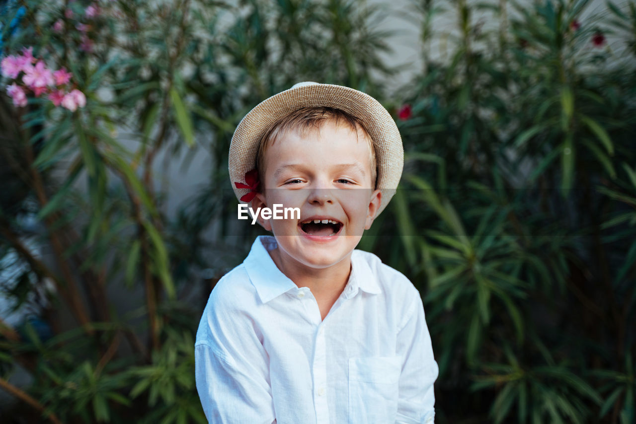 A boy in a straw hat and a white shirt is smiling. sincere laugh of a child. close-up portrait