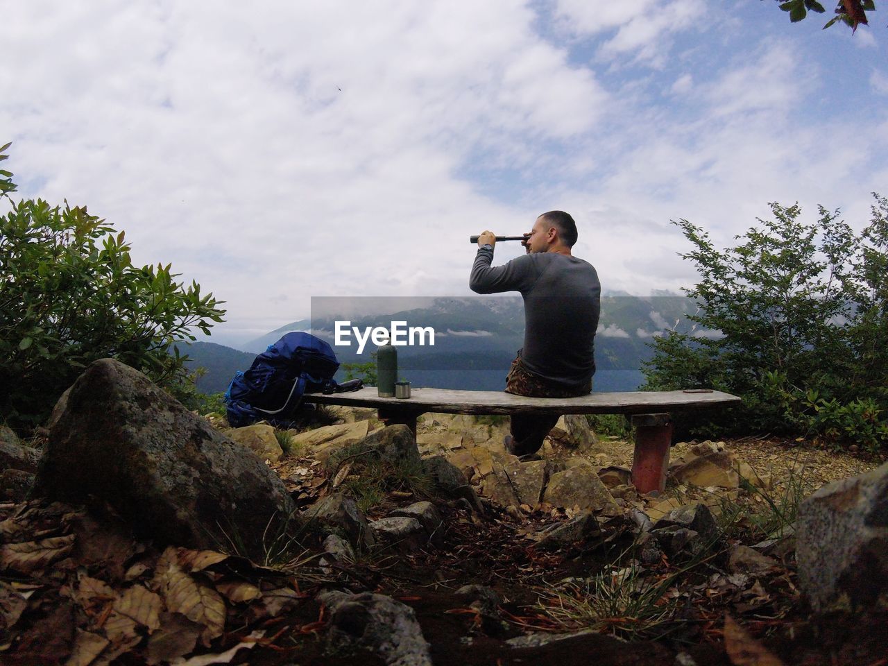 Man looking through binoculars against sky