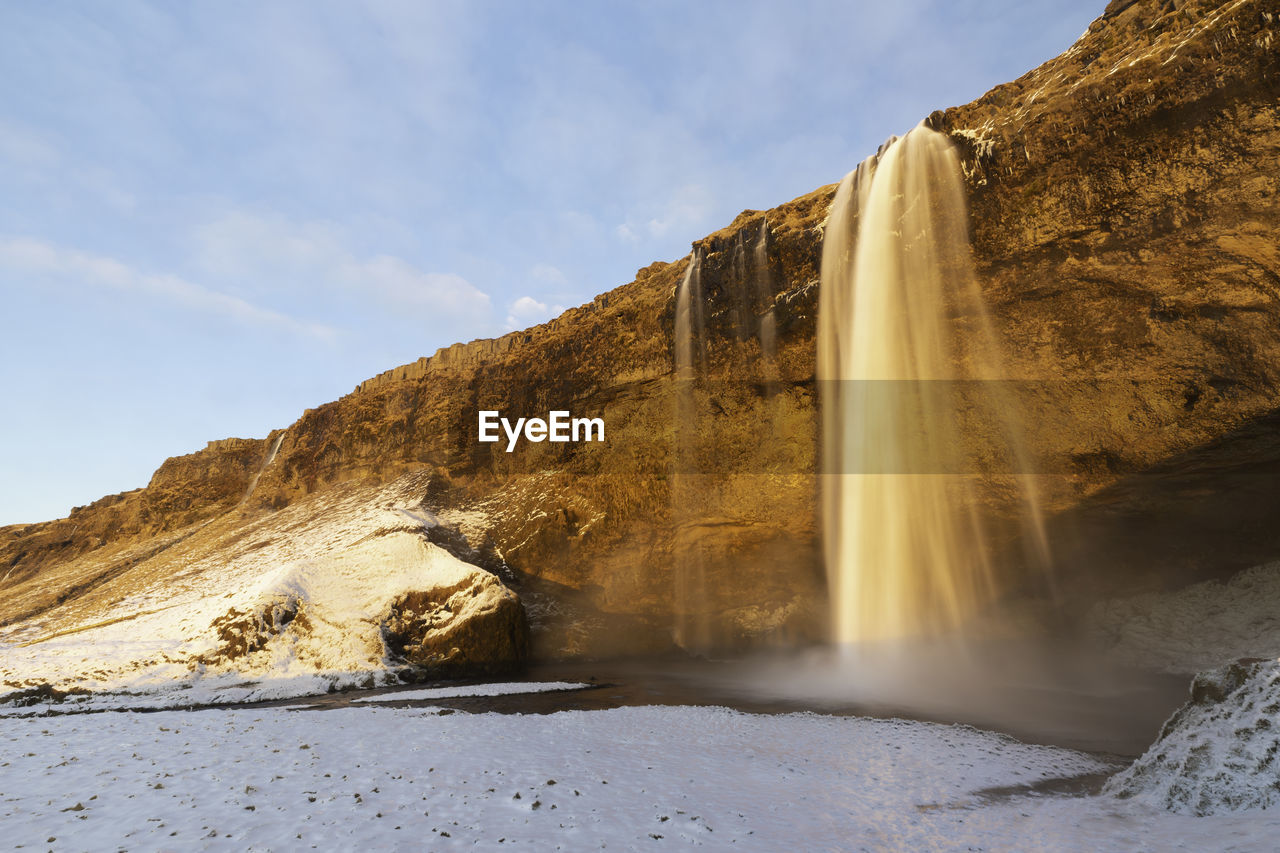 SCENIC VIEW OF WATERFALL AGAINST MOUNTAIN