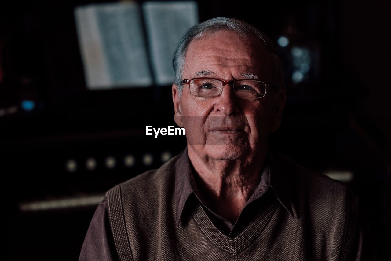 Portrait of senior man wearing eyeglasses in darkroom