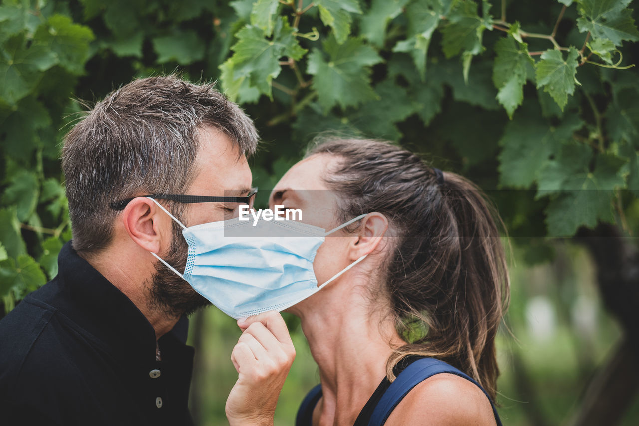 Couple of lovers kissing behind protective mask - normal lifestyle concept with couple in love kiss 