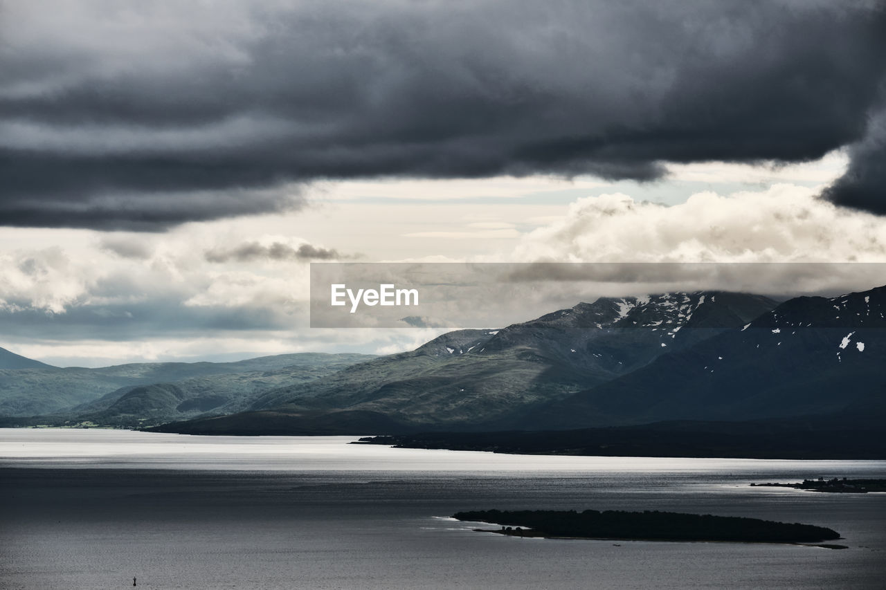 Scenic view of sea by mountains against sky in tromso