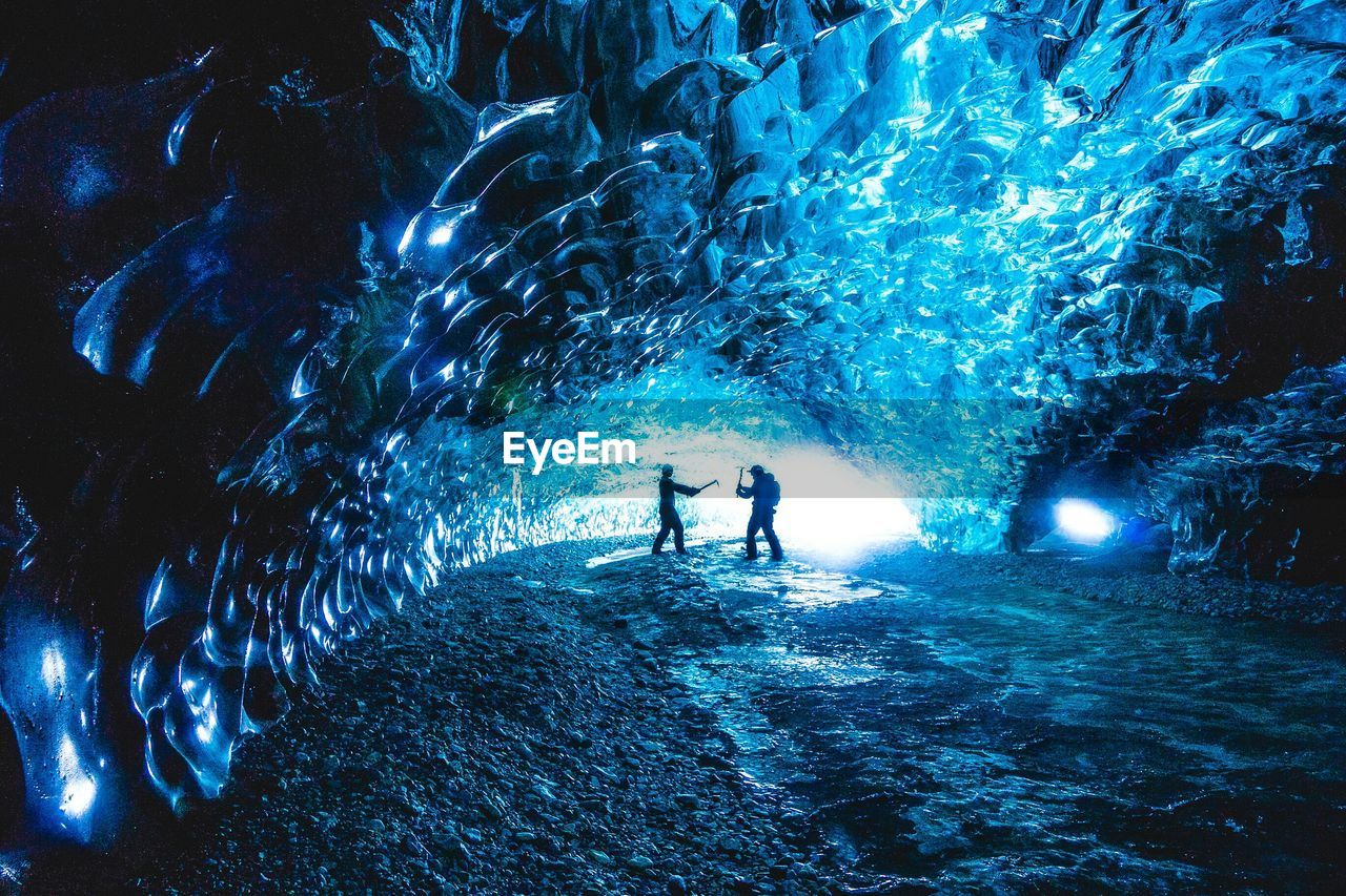 Side view of friends playing inside ice cave