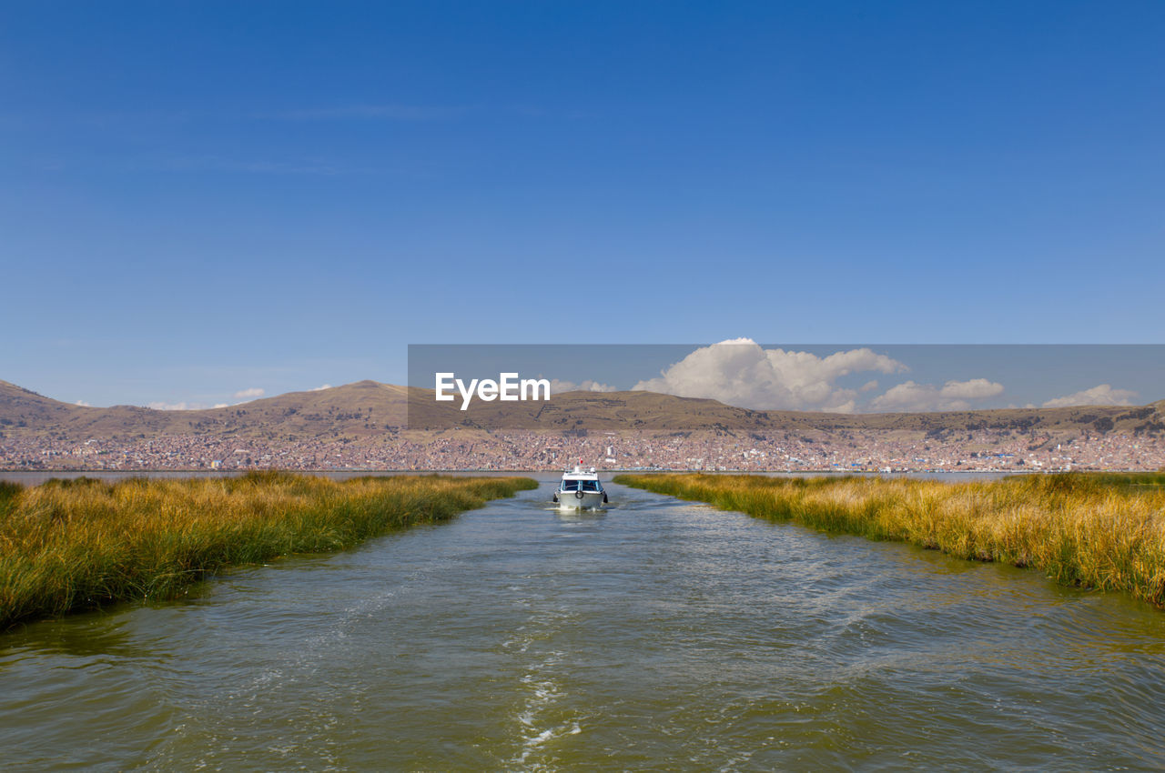 Man on riverbank against sky