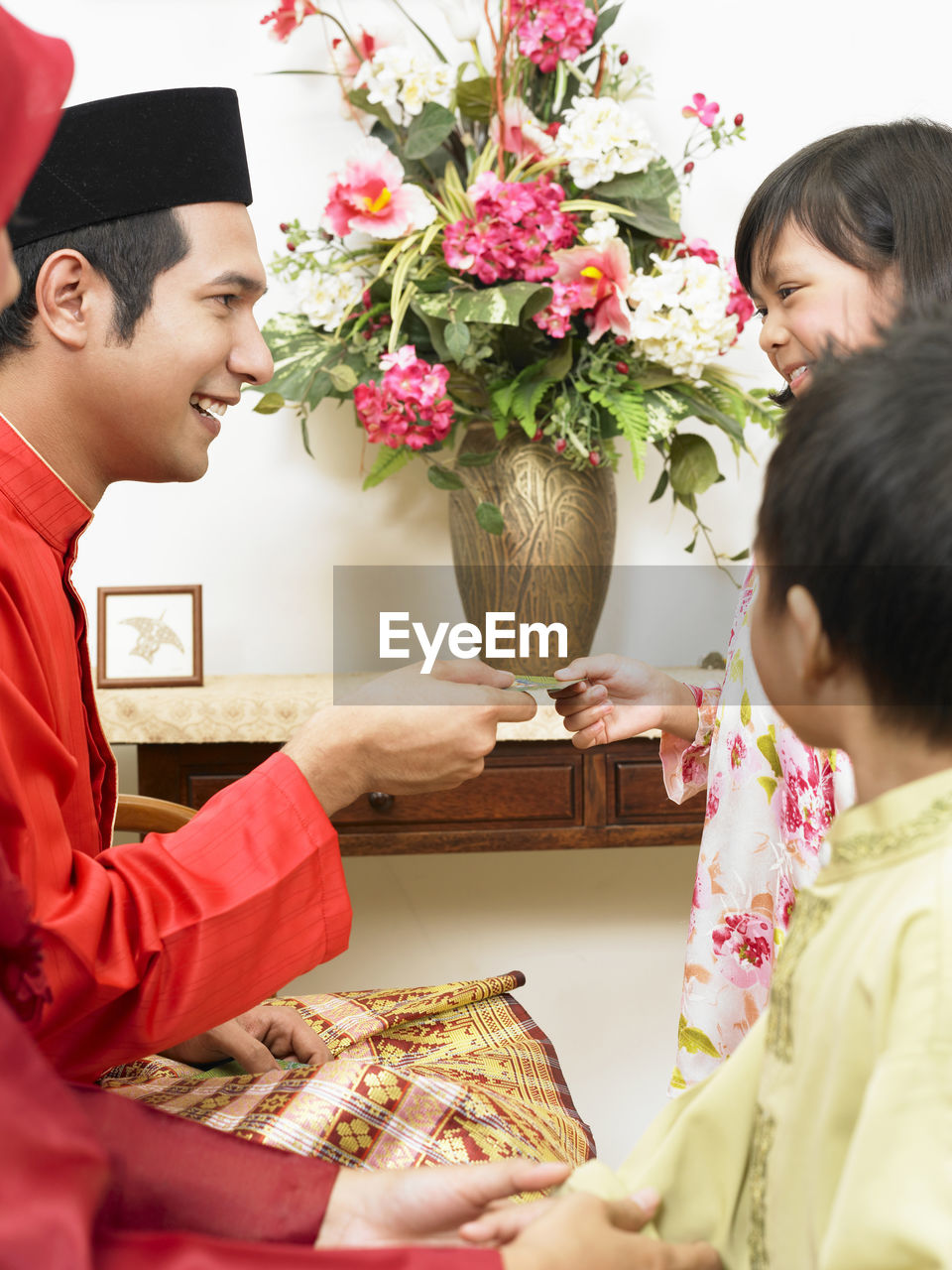 Father giving envelope to daughter at home