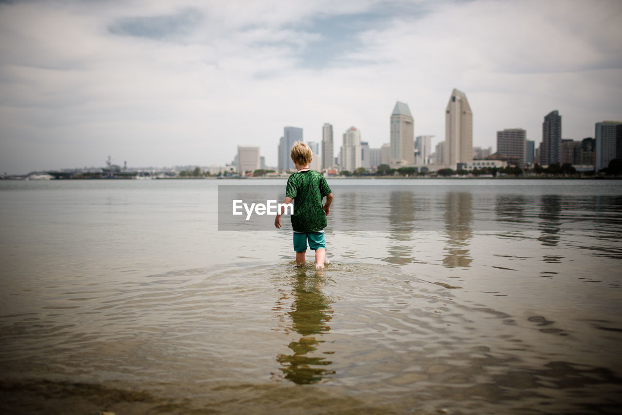 Six year old boy wading into coronado bay san diego skyline