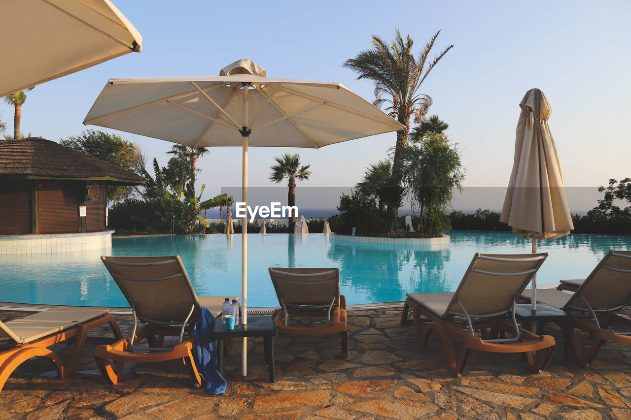 DECK CHAIRS BY SWIMMING POOL AGAINST SKY