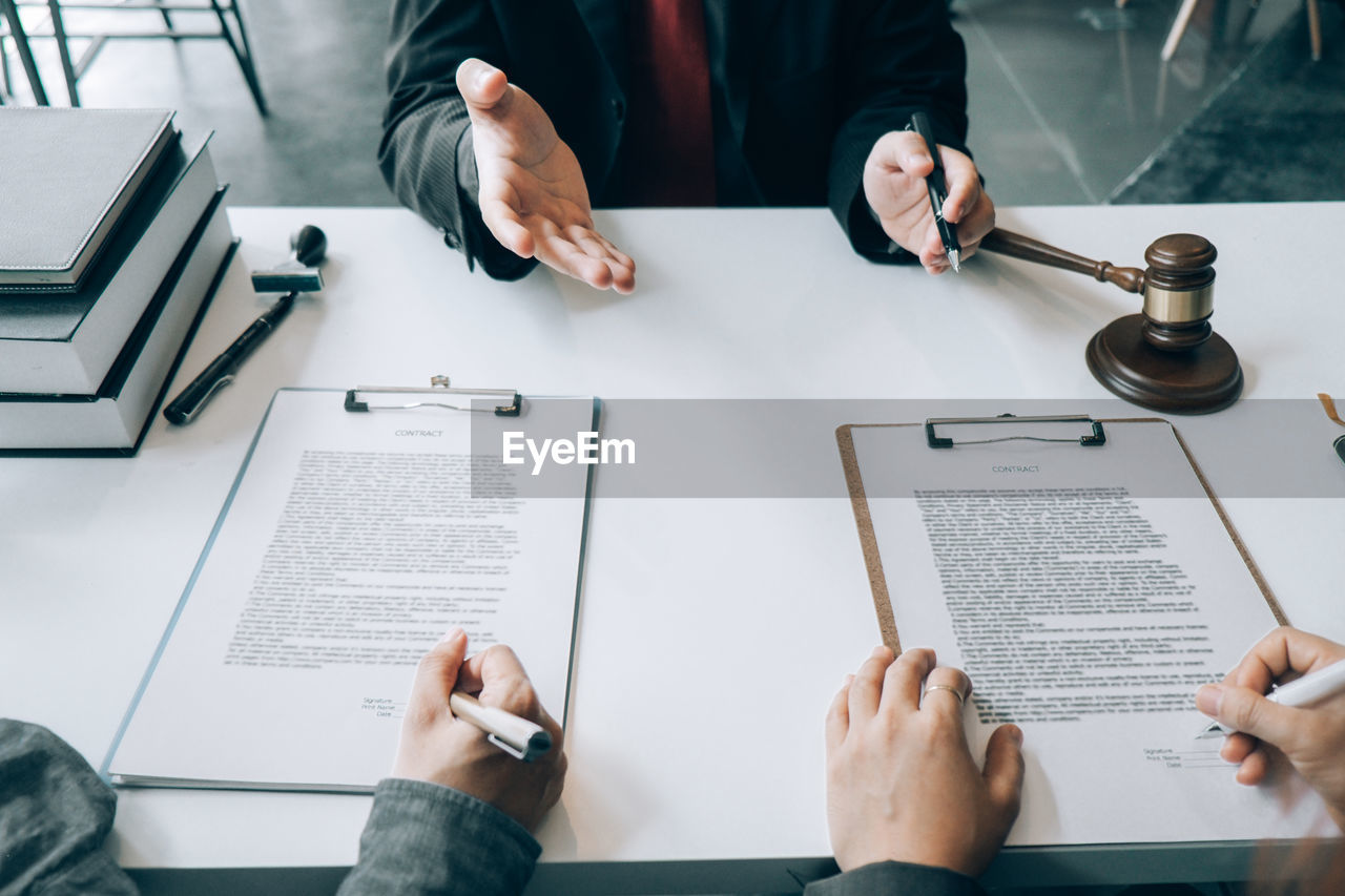 Cropped hands of lawyer gesturing while sitting at desk