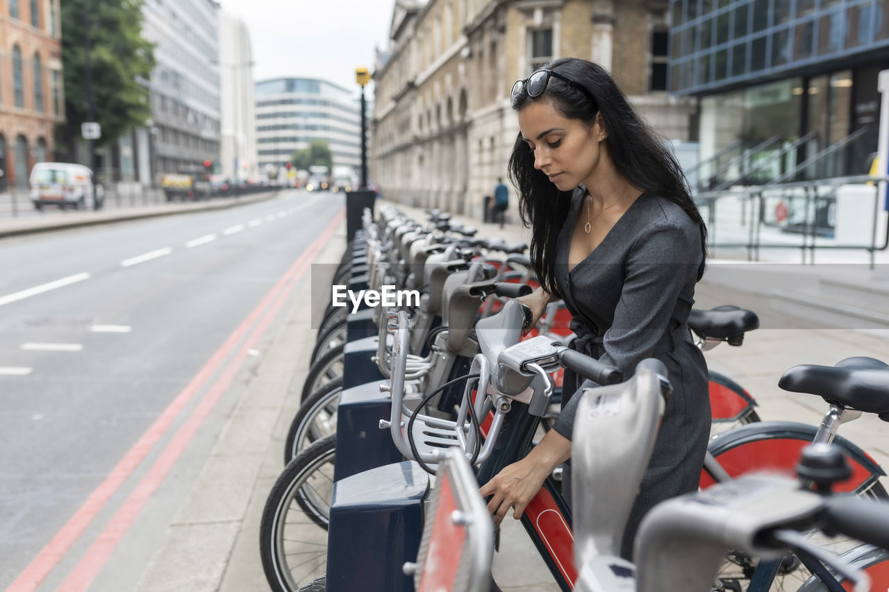 Woman in the city using bicycle hire for commuting, london, uk